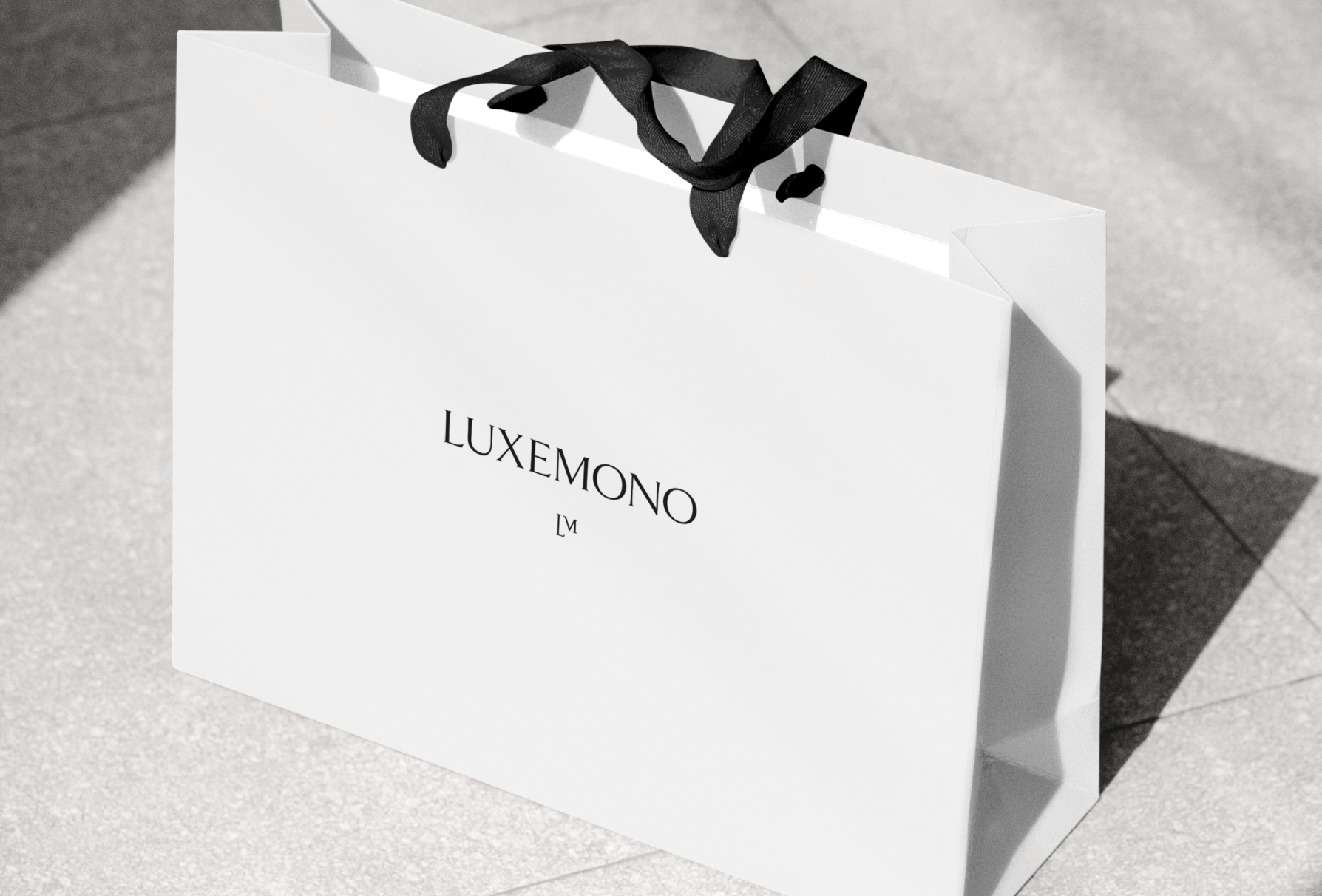 Luxemono's primary logo lockup on mock paper bag